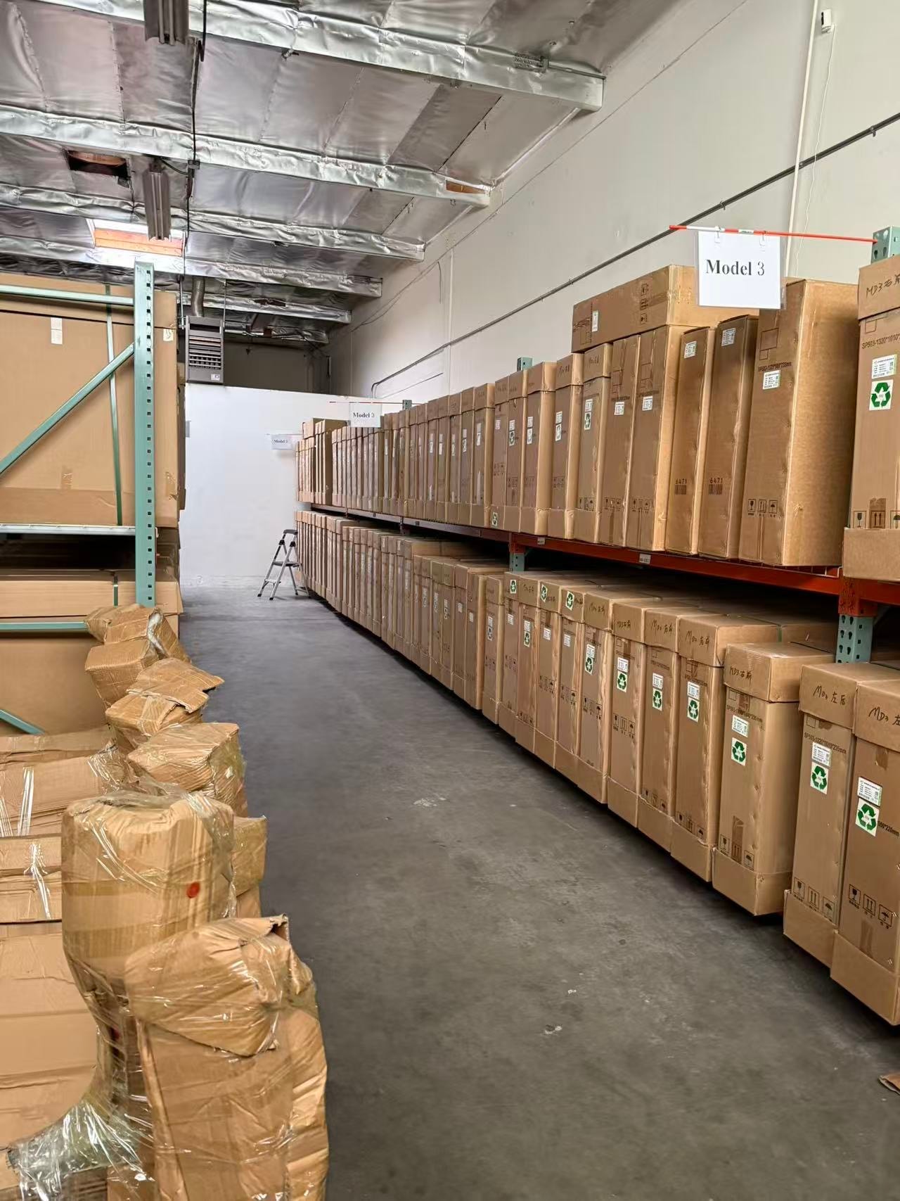 Model 3 parts organized on warehouse shelves